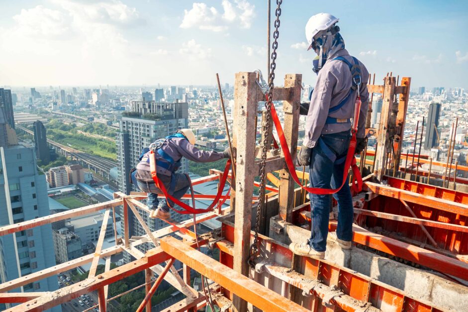 What is general liability insurance for contractors: construction workers standing on support beams on skyscraper being constructed